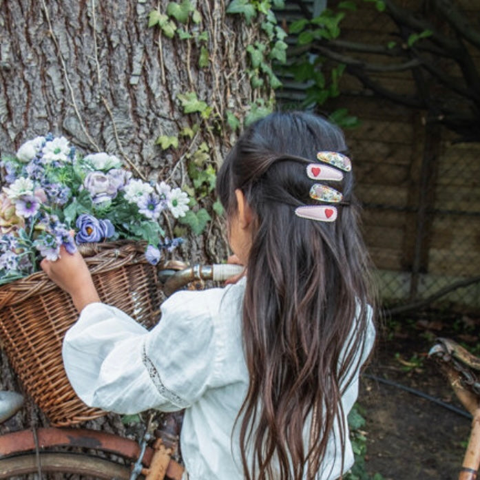 Person with long hair wearing our bramble fabric hair clips, holding a basket of flowers outdoors.