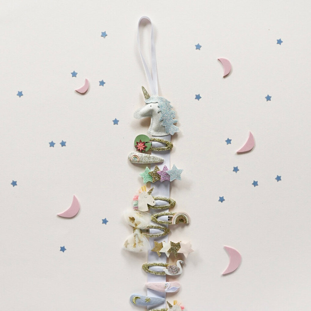 Decorative hair clip hanger in a unicorn and star design on a light background.
Showing what the clip hanger looks like in use