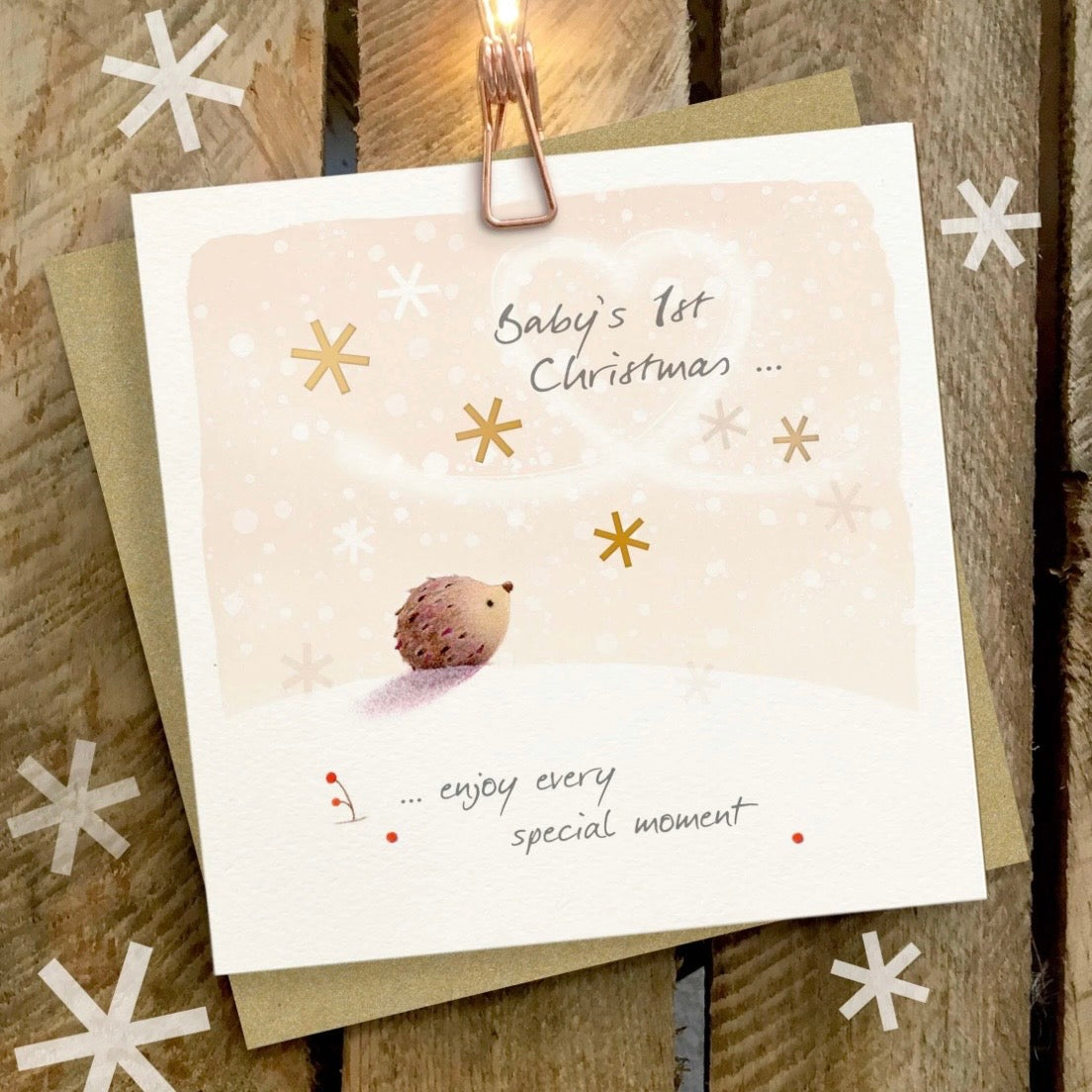 A square greeting card for baby's first Christmas, featuring a soft cream background with a small hedgehog illustration, gold star accents, and the text 'Baby's 1st Christmas.
Ginger Betty Cards
Christmas Cards
Christmas
1st Christmas
Baby's frist Christmas
Hedgehog
Printed in the UK