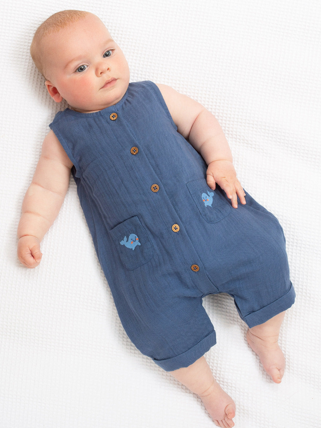 Baby wearing a blue romper with buttons on a white background

Navy Blue
Whale 
Dungarees
New baby gift
Baby clothing 
Organic cotton