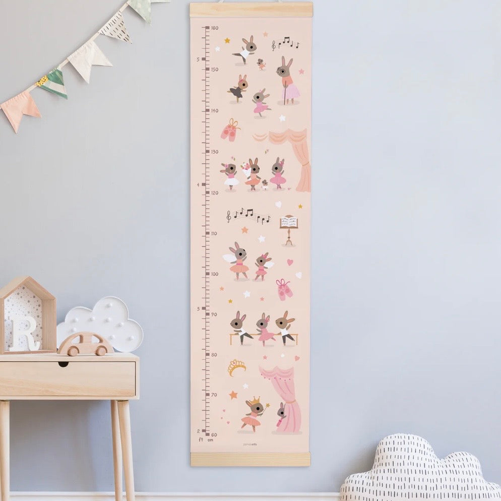 Growth chart with cartoon characters on a light blue wall above a wooden table.
