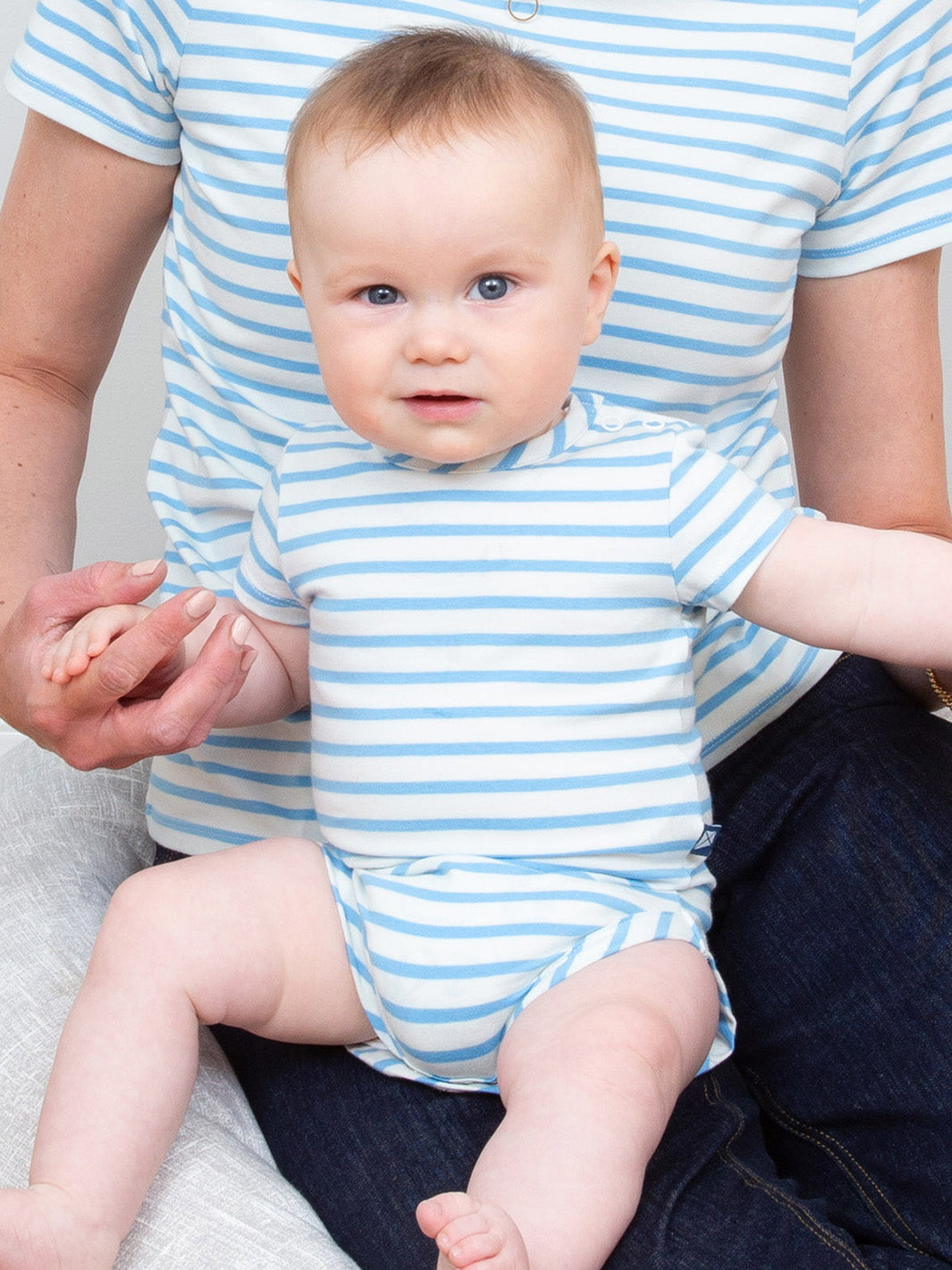 Baby wearing a blue and white striped onesie sitting on a person's lap.

Organic cotton 
Bodysuit
Stripes
Baby clothing 
New baby gift