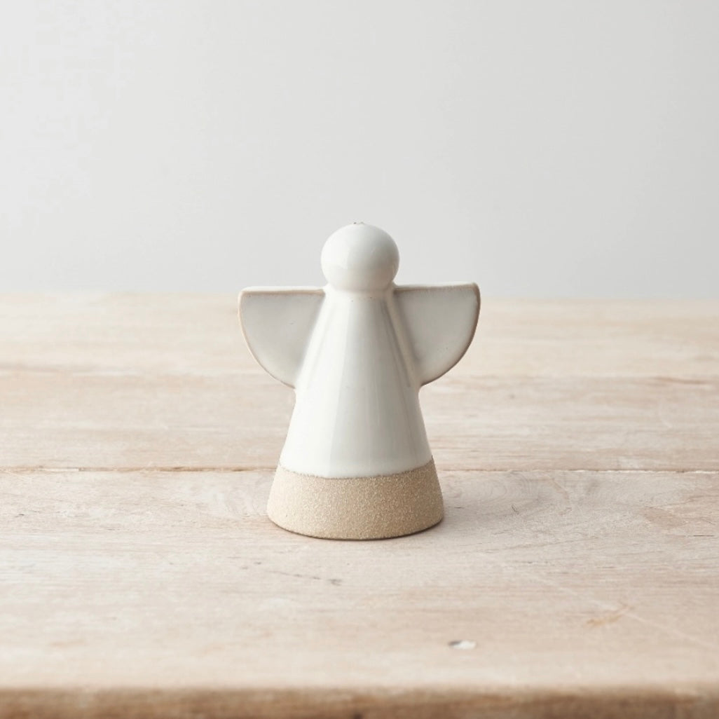 White ceramic angel figurine on a wooden surface with a light gray background