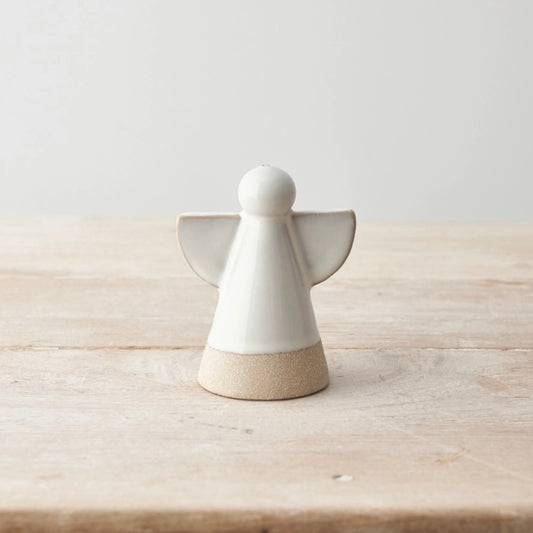 White ceramic angel figurine on a wooden surface with a light gray background