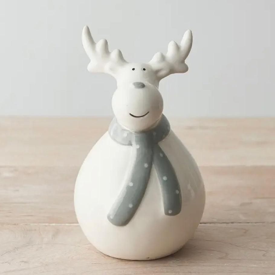 Ceramic reindeer figurine with a gray scarf on a wooden surface