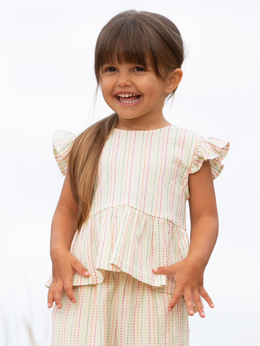 Young girl wearing a stripe ruffled blouse with a plain background

Blouse
Children's clothing 
Organic cotton 
Kite clothing 
Stripes 
Cotton 
Summer
Summer clothing 