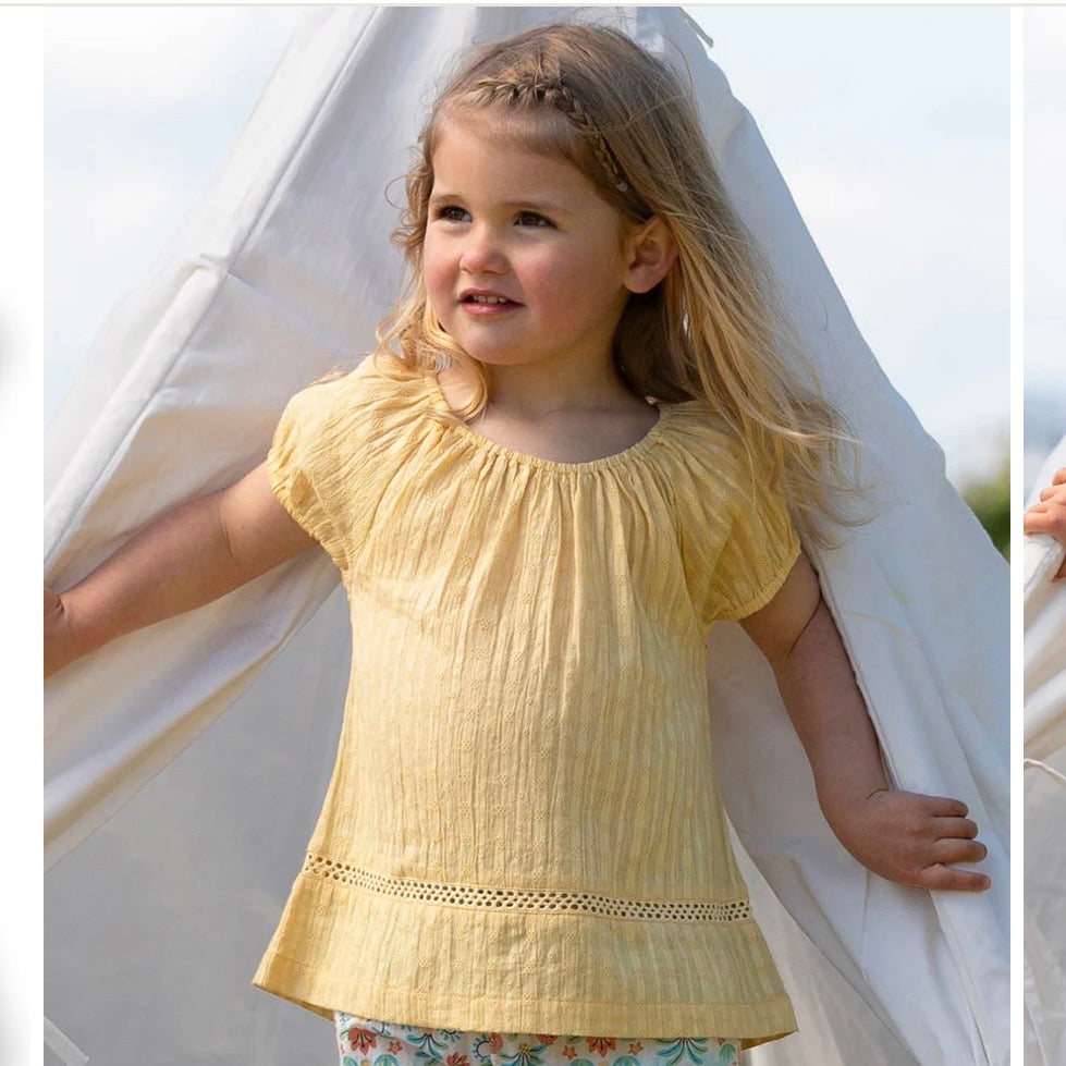 Young girl wearing a yellow top with a white background

Children's clothing 
Yellow
Blouse
Organic cotton 
Summer clothing 
Summer