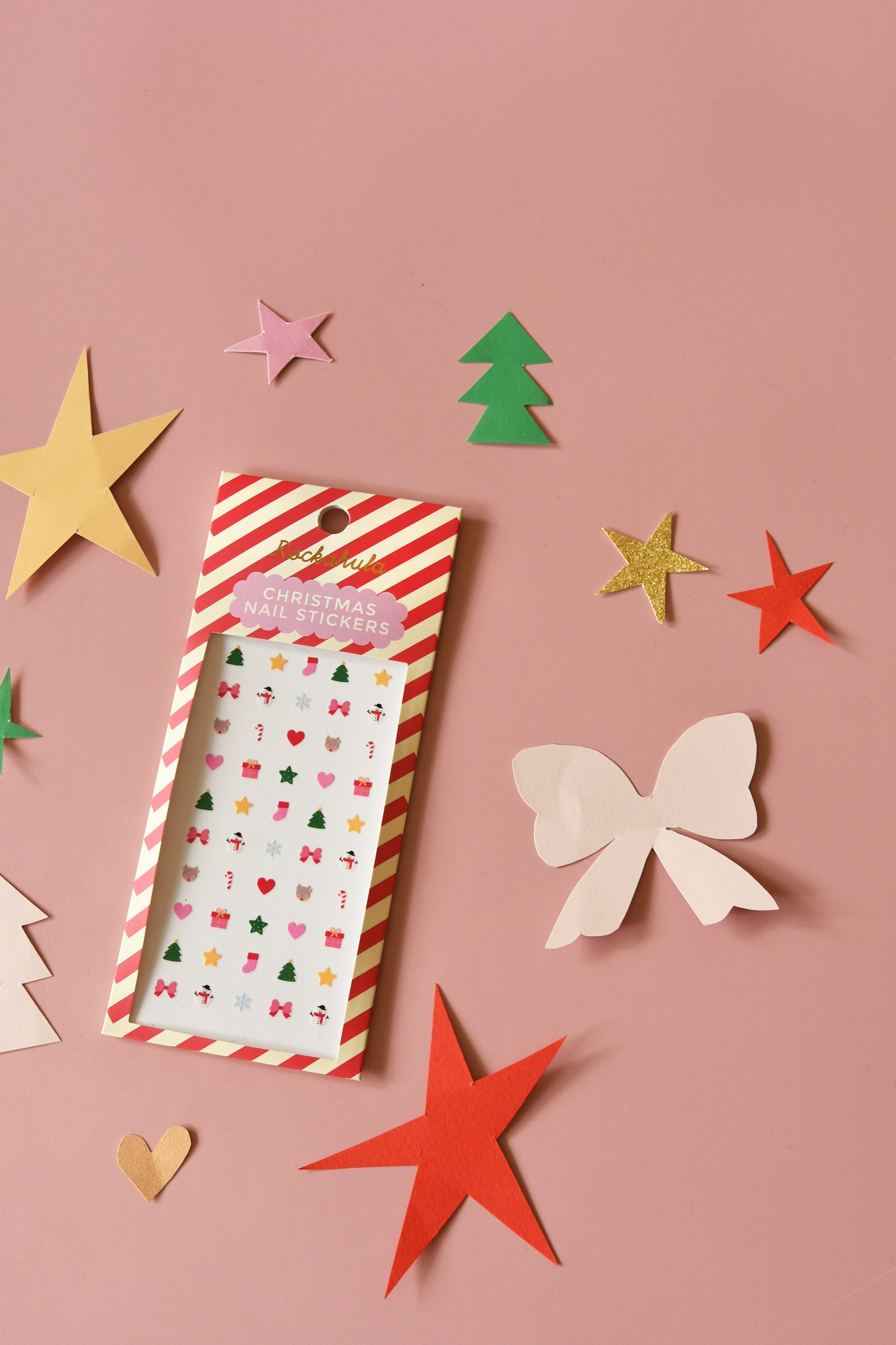Pack of decorative stickers with festive designs on a pink background with paper cutout shapes.