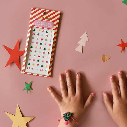 Children's hands with Christmas stickers on a pink background