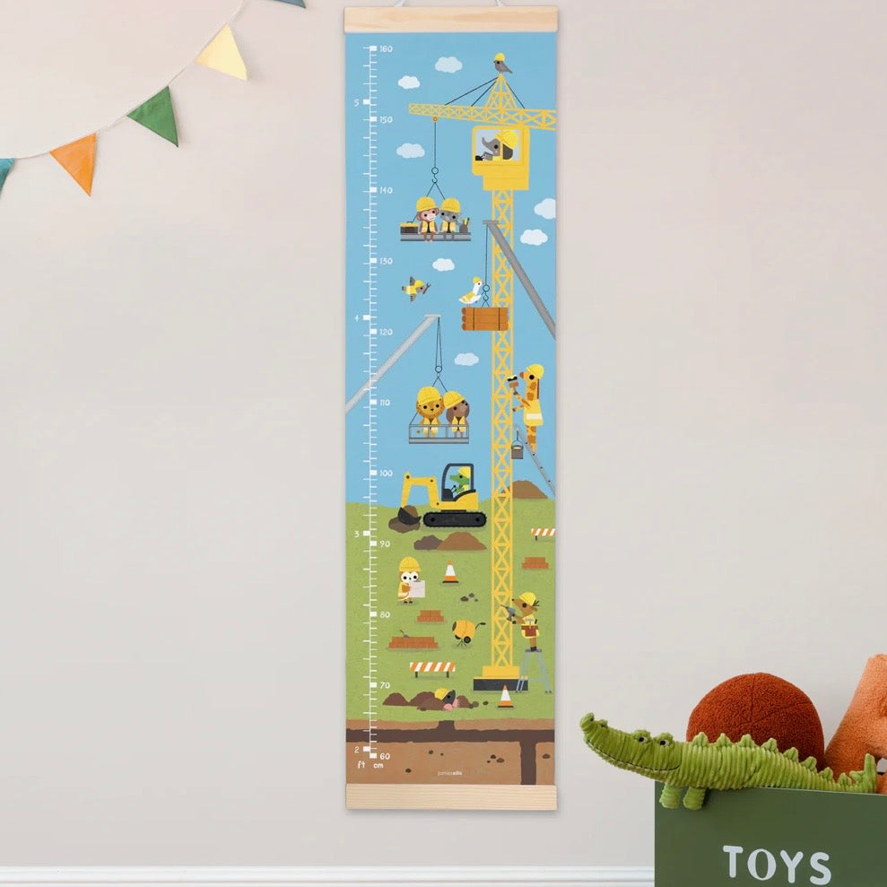 Growth chart with construction theme on a wall next to toys