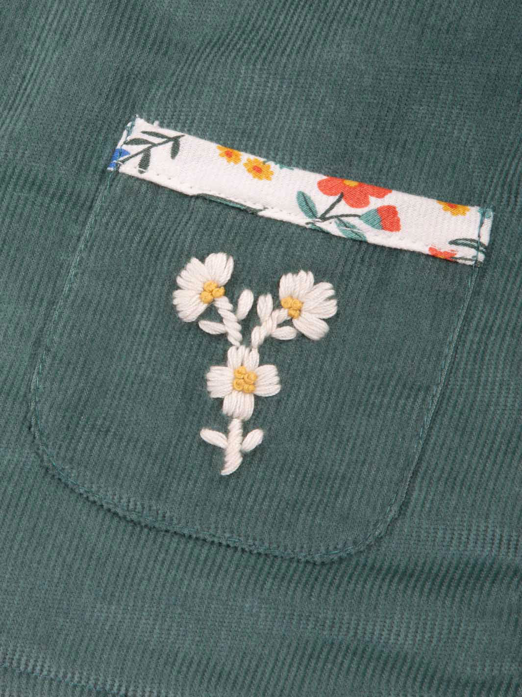 Green jacket with floral embroidery on a pocket and matching fabric strip.