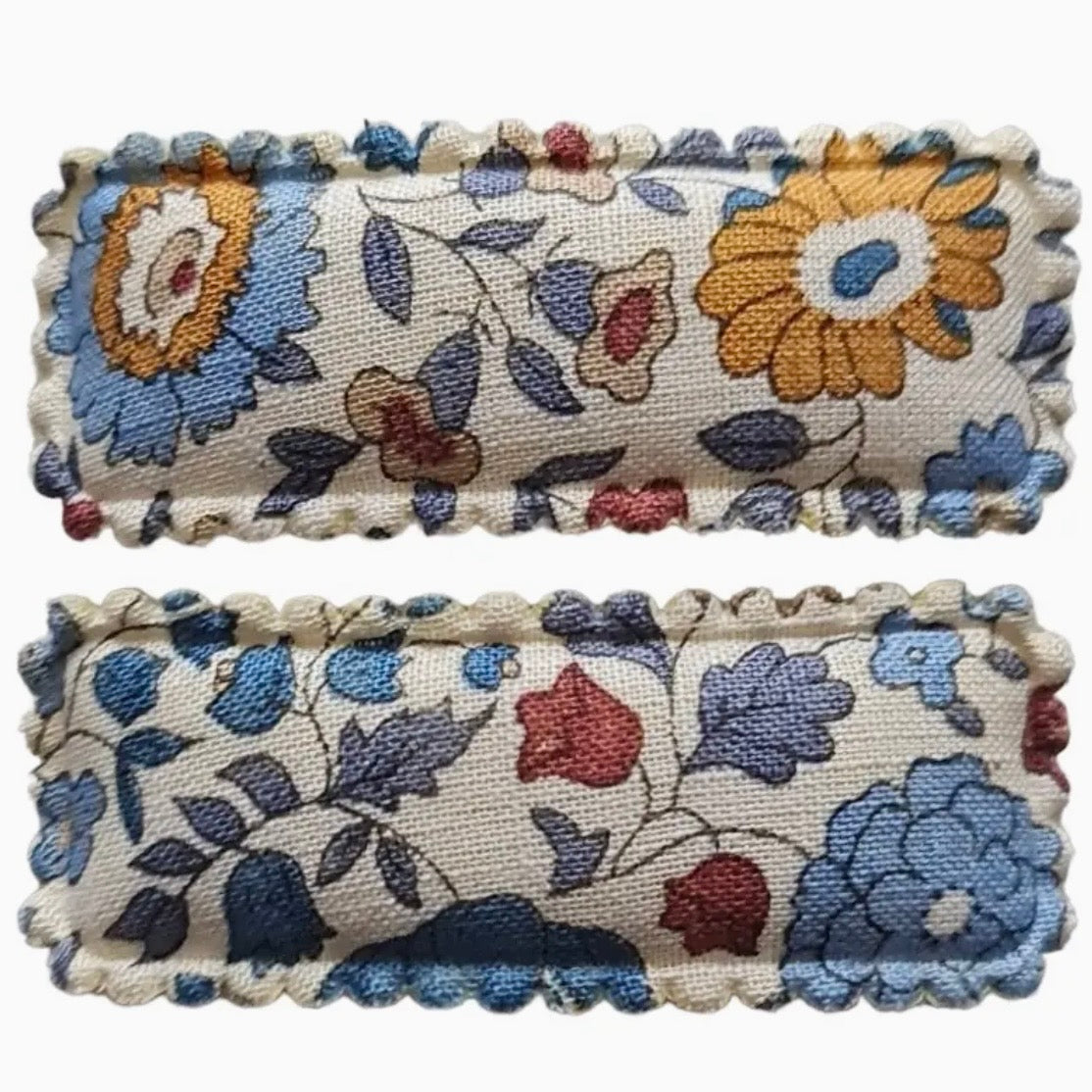 Two rectangular embroidered fabric hair clips with scalloped edges, featuring a floral pattern in blue, yellow, red, and purple on a cream background.

Hair Clips
Liberty Print
Gift inspiration 
Floral
Girls Hair Accessories
