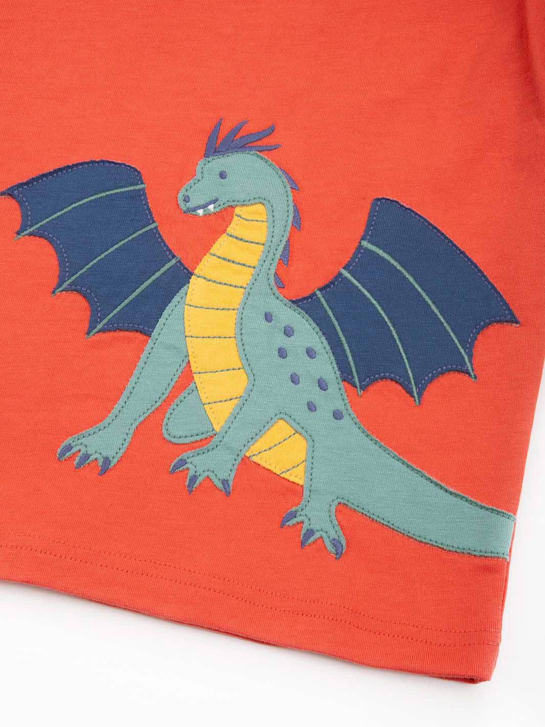 Close of of dragon appliqué on orange t-shirt  