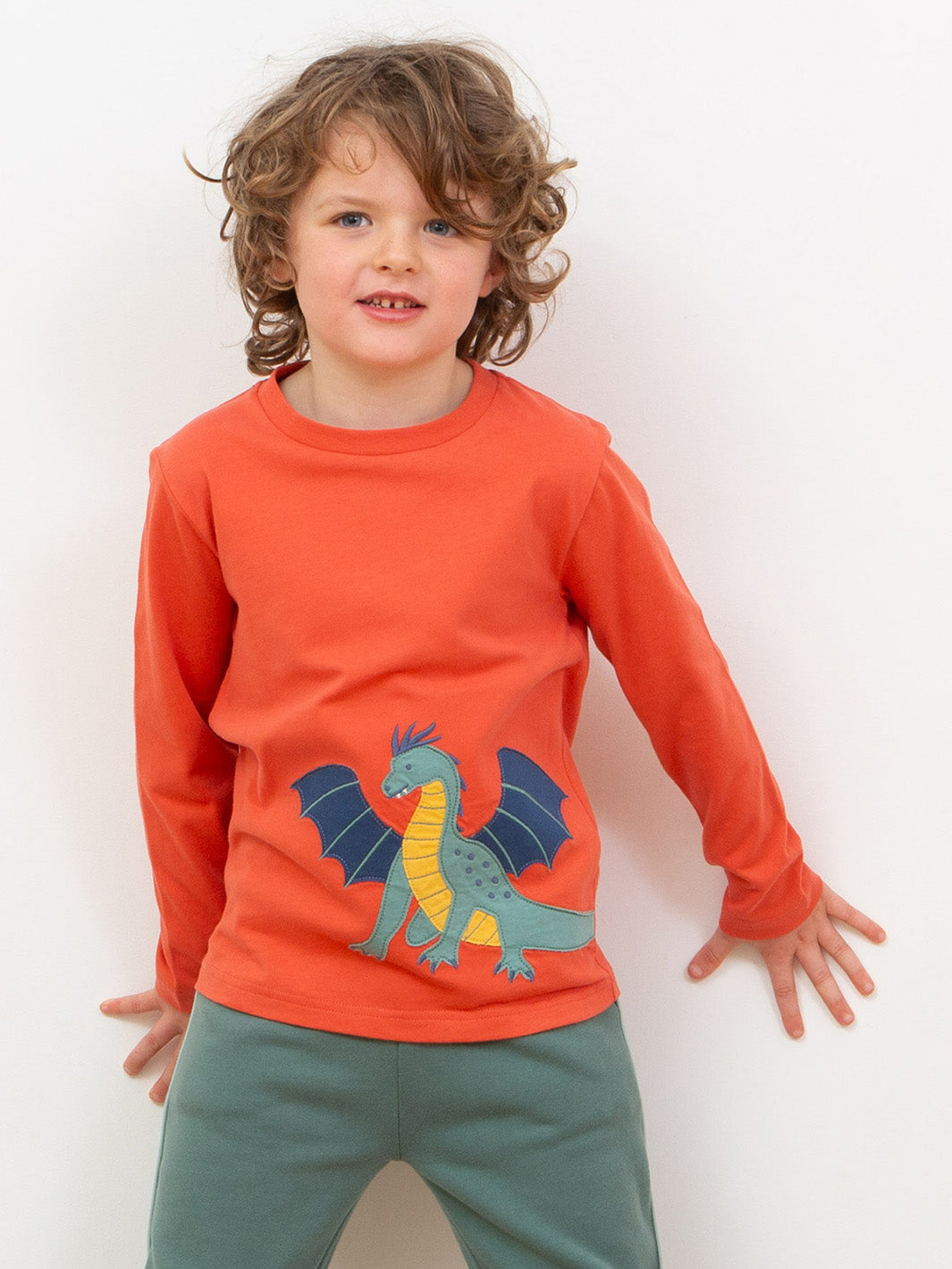 Boy wearing a orange t-shirt with a dragon appliqué 
