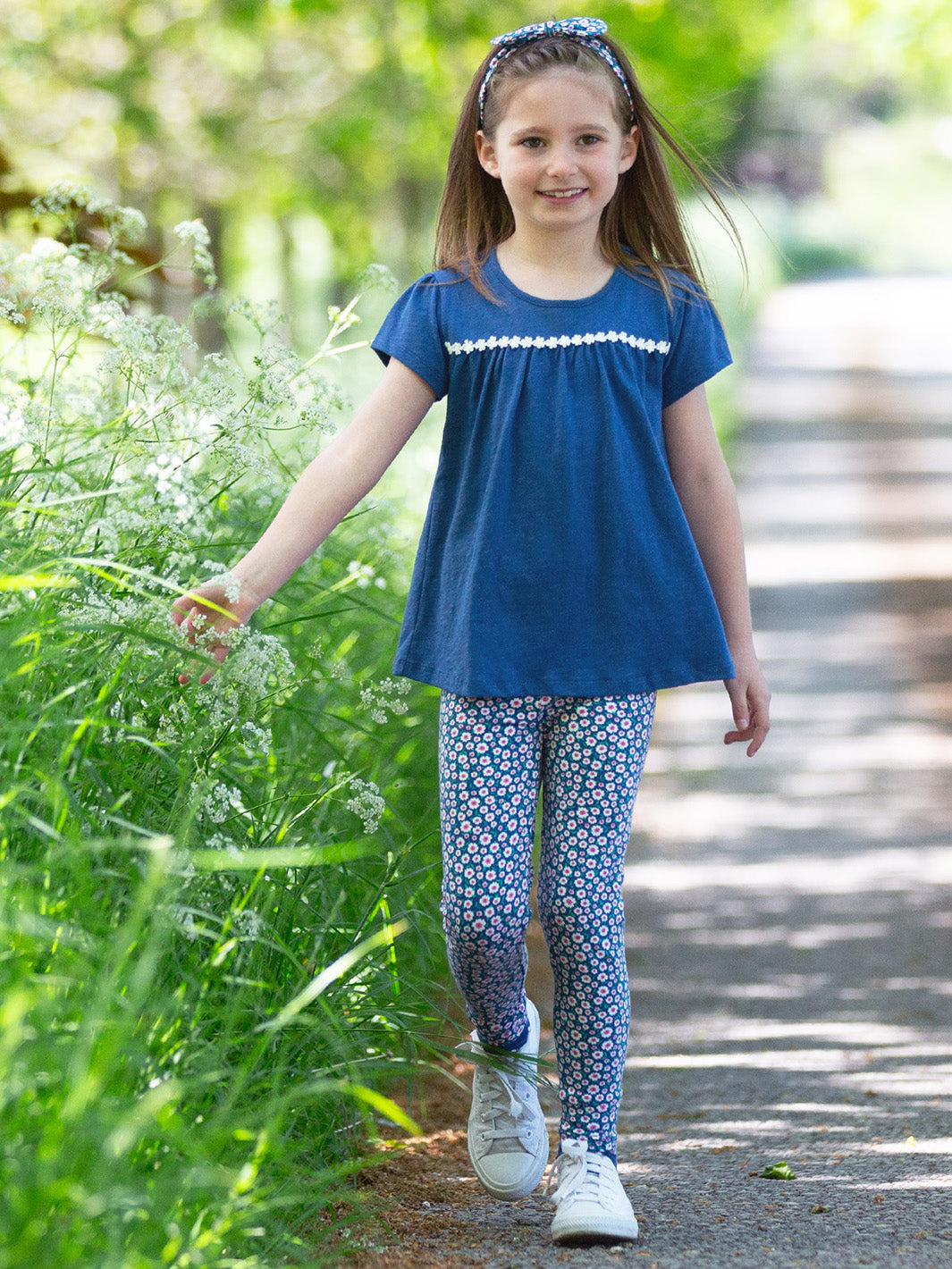 Young girl in a blue top and patterned leggings walking on a path with greenery.
Organic children's clothing 
, made to be worn 
