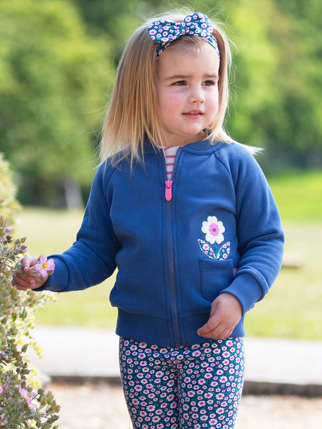 Young girl wearing a blue jacket with a floral design outdoors
Made from organic cotton