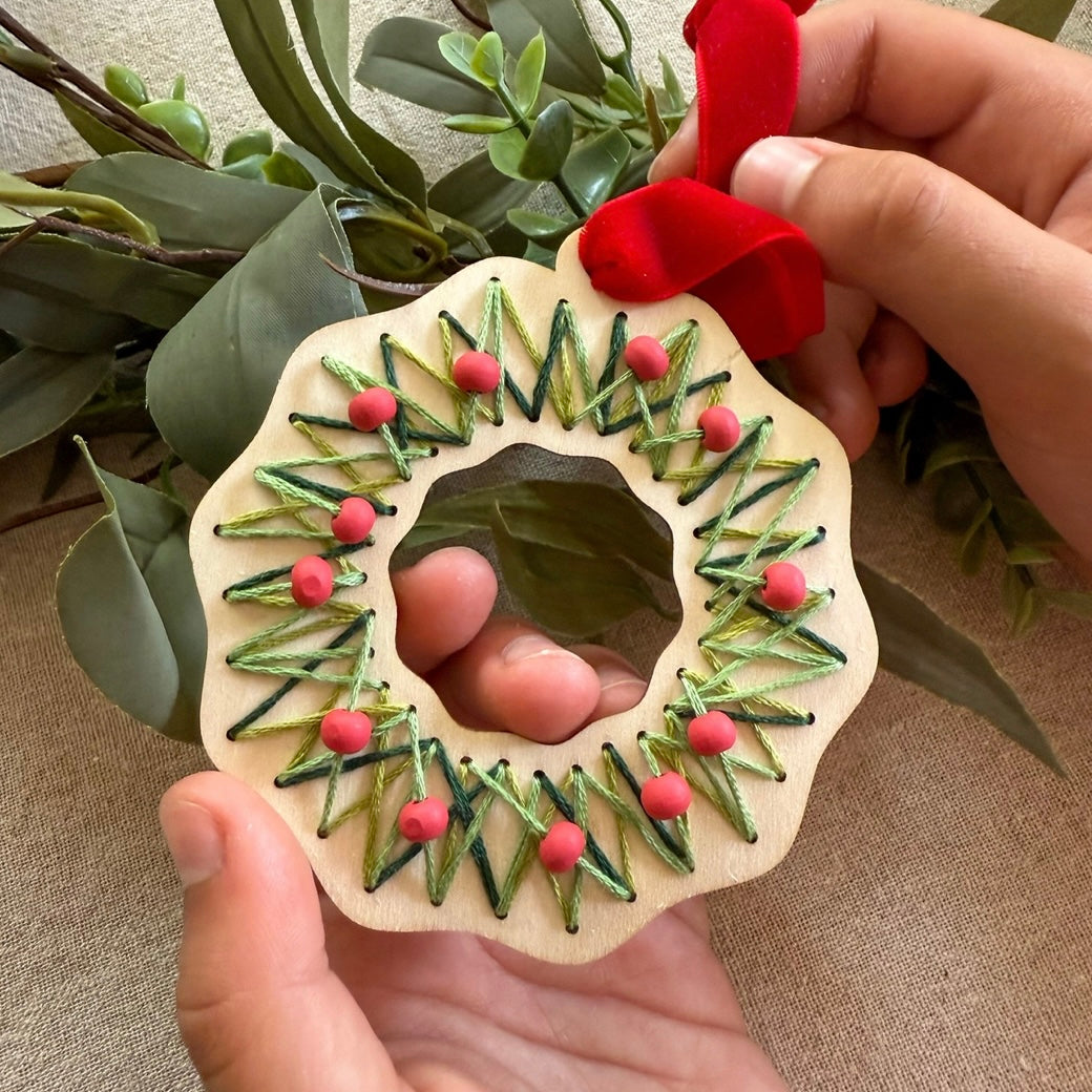 Child creating a stitched Christmas wreath
