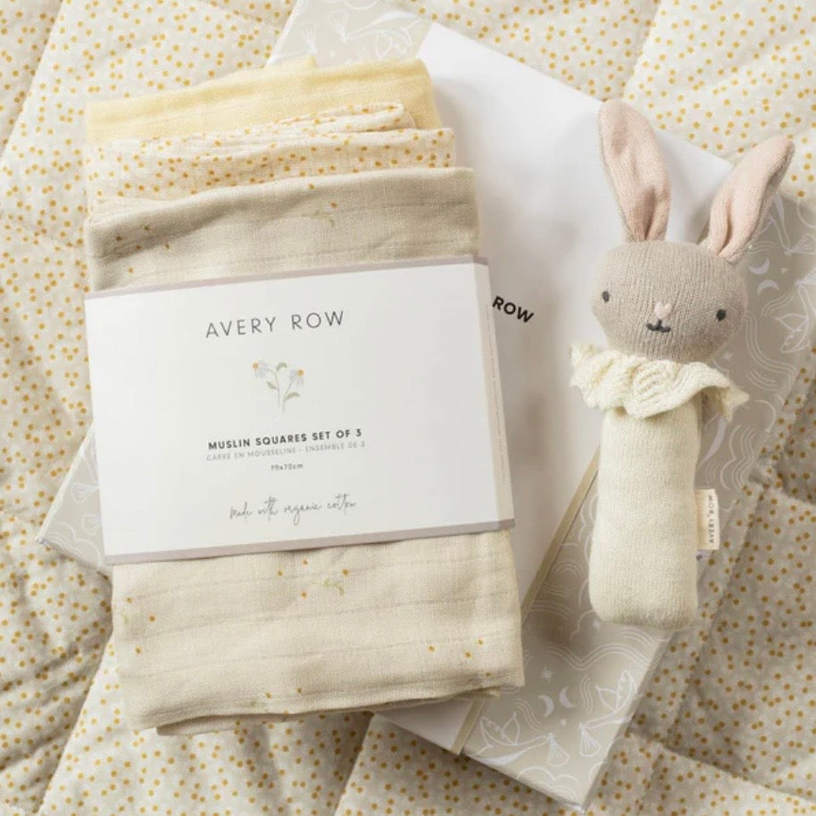 Baby gift set with muslin squares and a plush toy on a patterned fabric background, featuring the brand 'Avery Row'.