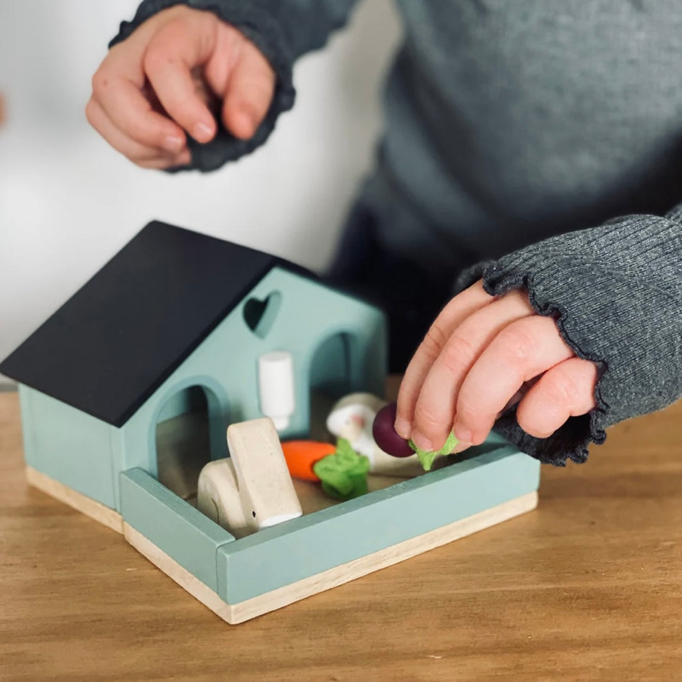 Child playing with a wooden play set. 
Rabbit hitch with rabbits, carrot and turnip 