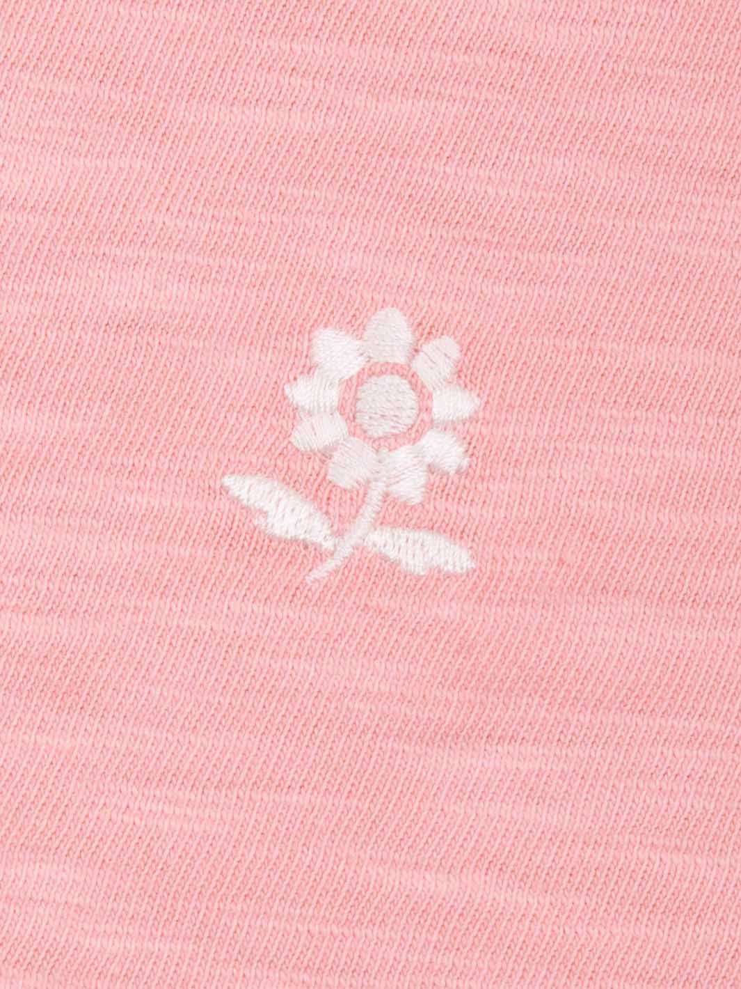 White embroidered flower design on a pink tunic- close up