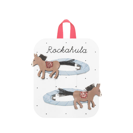 Packaged hair accessories with horse designs on a white background, featuring the brand 'Rockahula'.