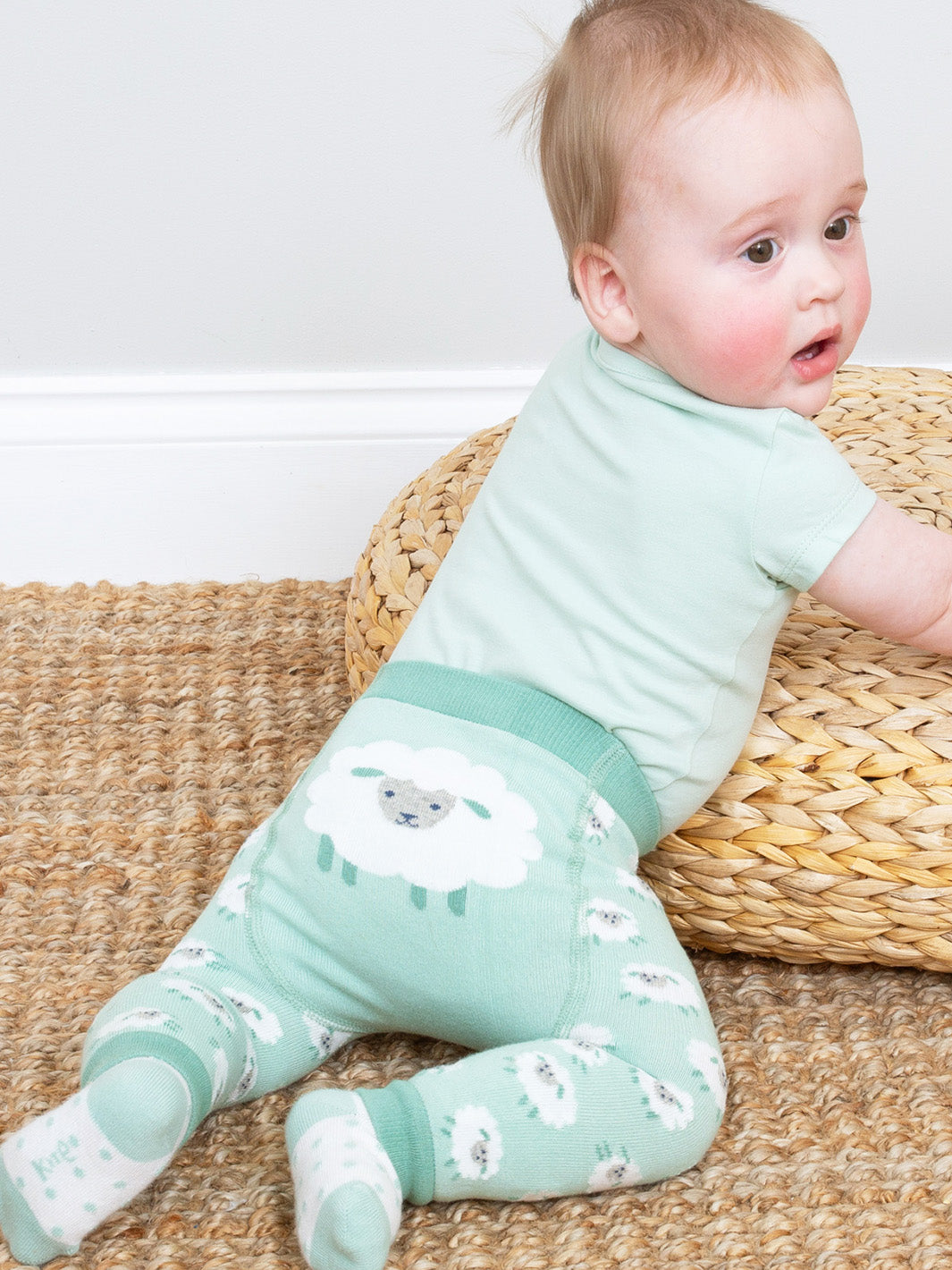 Baby wearing a green outfit with animal prints sitting on a woven mat.
For ease and comfort, pull them on with a t-shirt, baby vest or dress