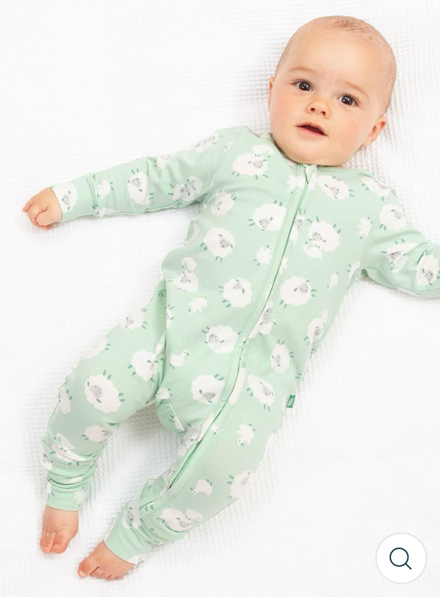 Baby wearing our sheep sleepsuit with  on a white background