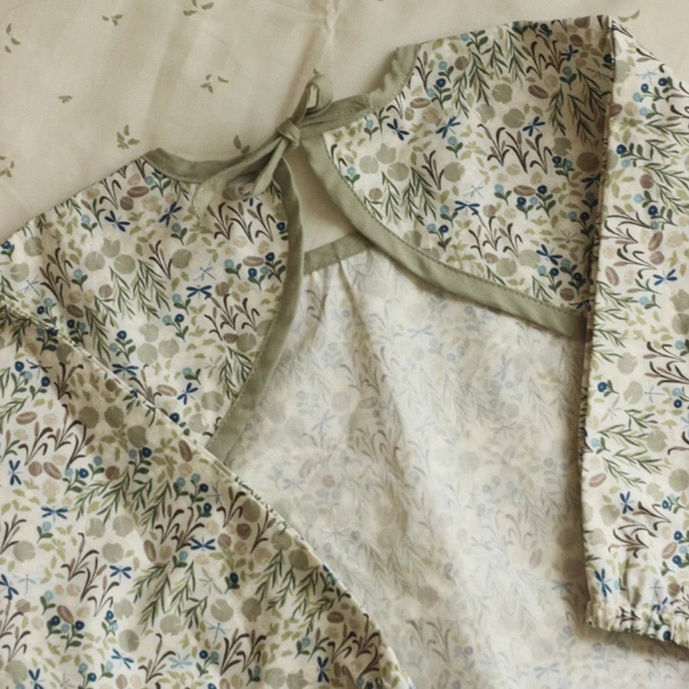 Floral-patterned sleeved bib with a plain centre on a neutral background
