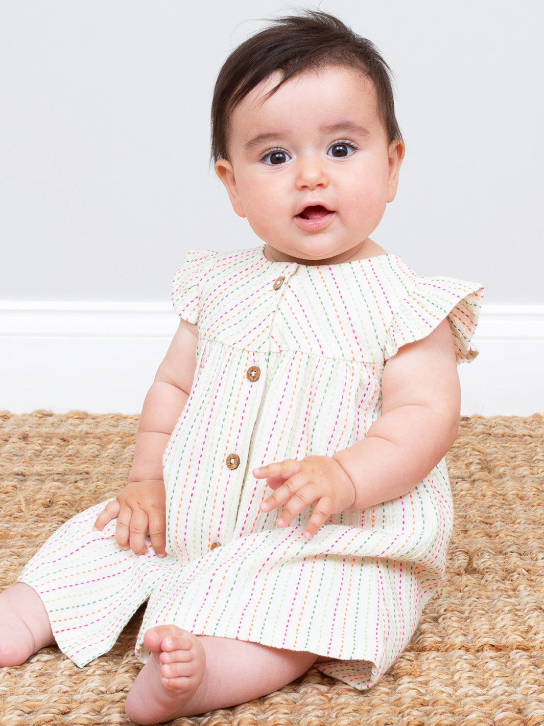 Baby wearing a white dress with colourful stripe patterns sitting on a woven mat.

Dress
Baby clothing 
New baby gift
Baby clothes 
Organic cotton