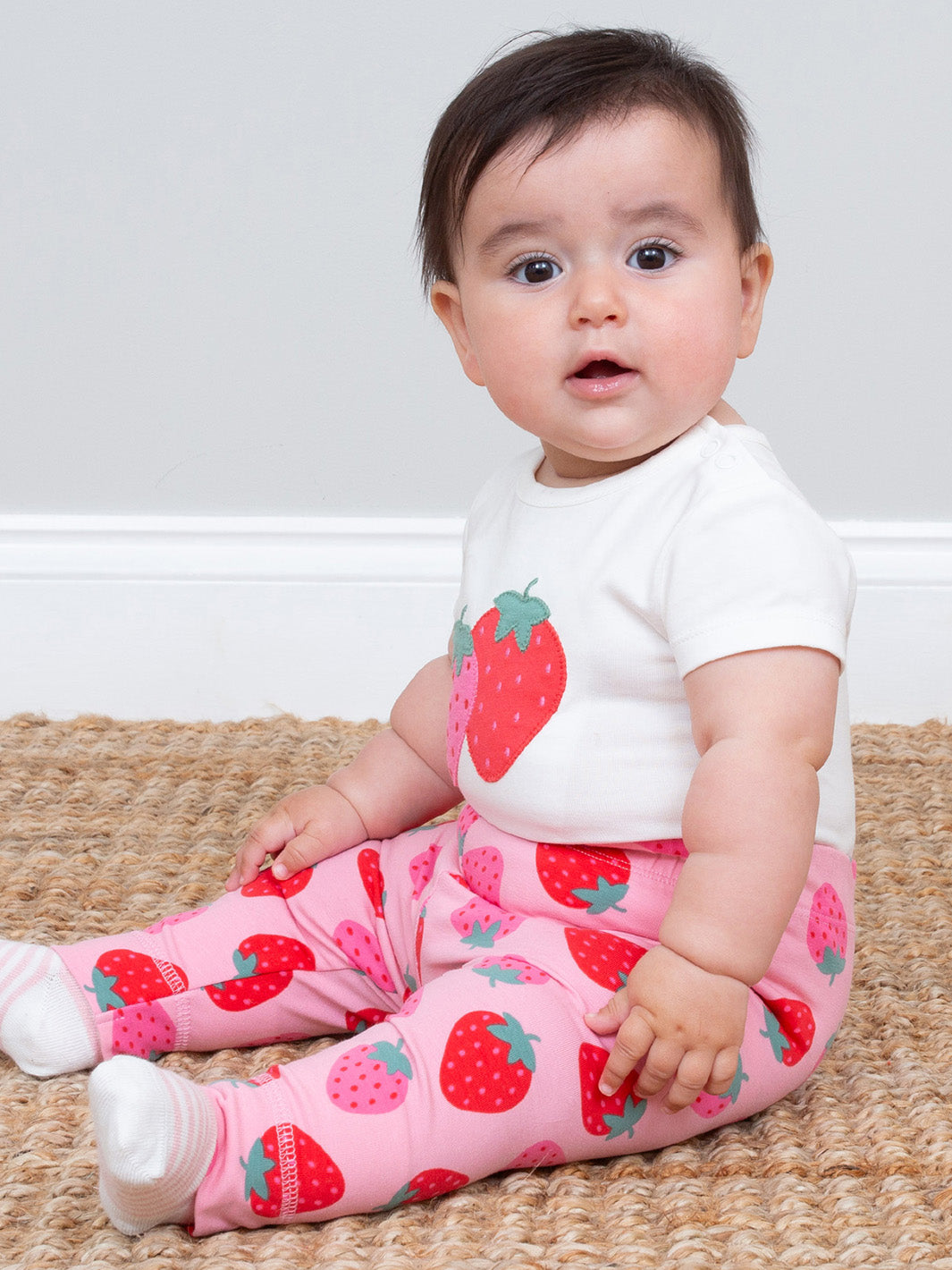 Baby wearing a white bodysuit and matching pink strawberry-patterned leggings sitting on a woven mat.

Baby clothing
Leggings
New baby gifts 
Organic cotton 
Kite clothing