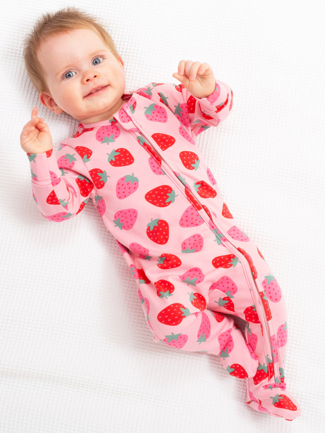 Baby wearing a pink strawberry-patterned onesie on a white background

Organic cotton 
Baby clothing 
GOTS Certified fabrics 
New baby gift
Baby shower gift
Kite clothing