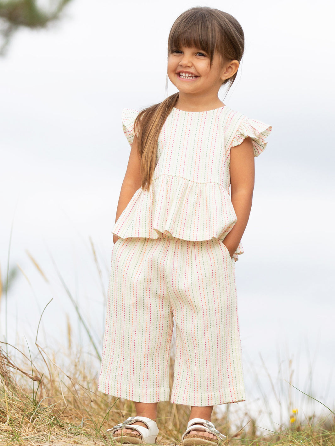 Young girl in a white ruffled top and striped trousers standing in a grassy field.

Children's clothing 
Kids clothes
Organic cotton 
Stripes 
Trousers
Pull Ups