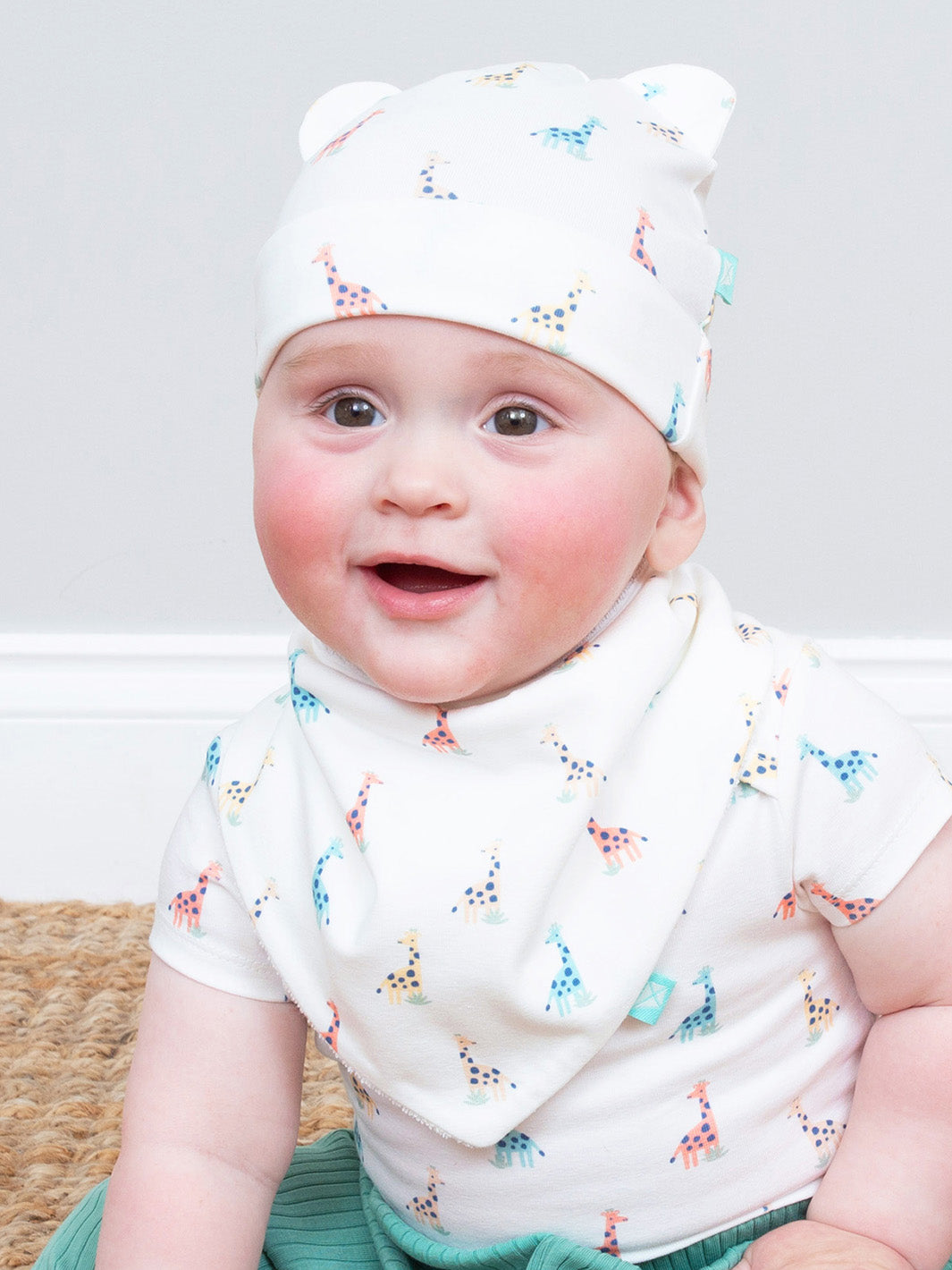 Baby wearing a white hat with colourful giraffe print and a matching outfit on a light background

Organic cotton 
Baby hat 
New baby gifts
Giraffe
Kite clothing 