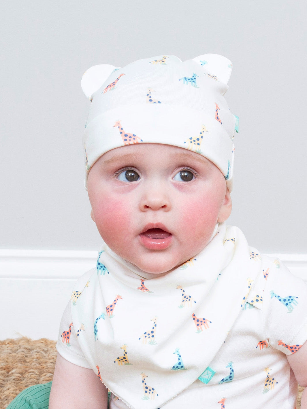 Baby wearing a white hat with a colourful giraffe print and a matching bib on a light gray background

Giraffe 
Kite clothing 
Organic cotton 
GOTS Certified fabric 
New baby 
Baby clothing 