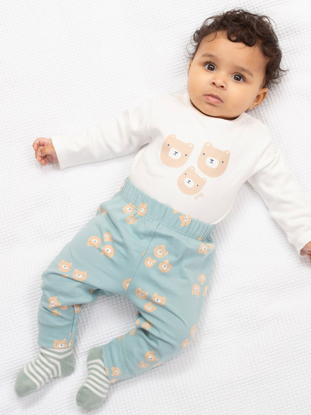Baby wearing a white long-sleeve shirt with bear designs and light blue pants with bear patterns on a white background.