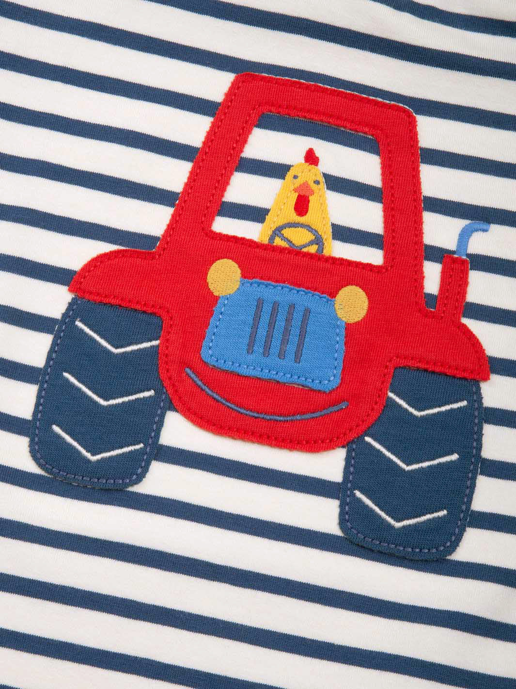 Red tractor patch on a striped shirt with a yellow character inside