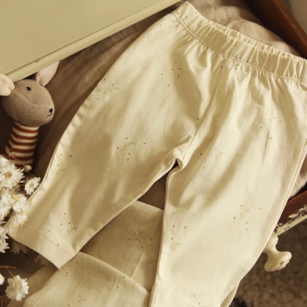 Beige leggings with a delicate floral  with a soft texture on a wooden surface 
A lovely new baby gift